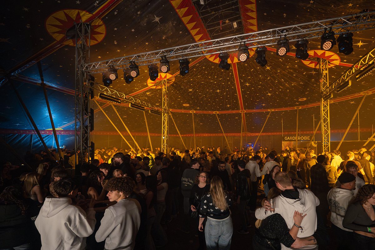 Volles Veranstaltungszelt bei Nacht, Bühnenlicht über der Menge